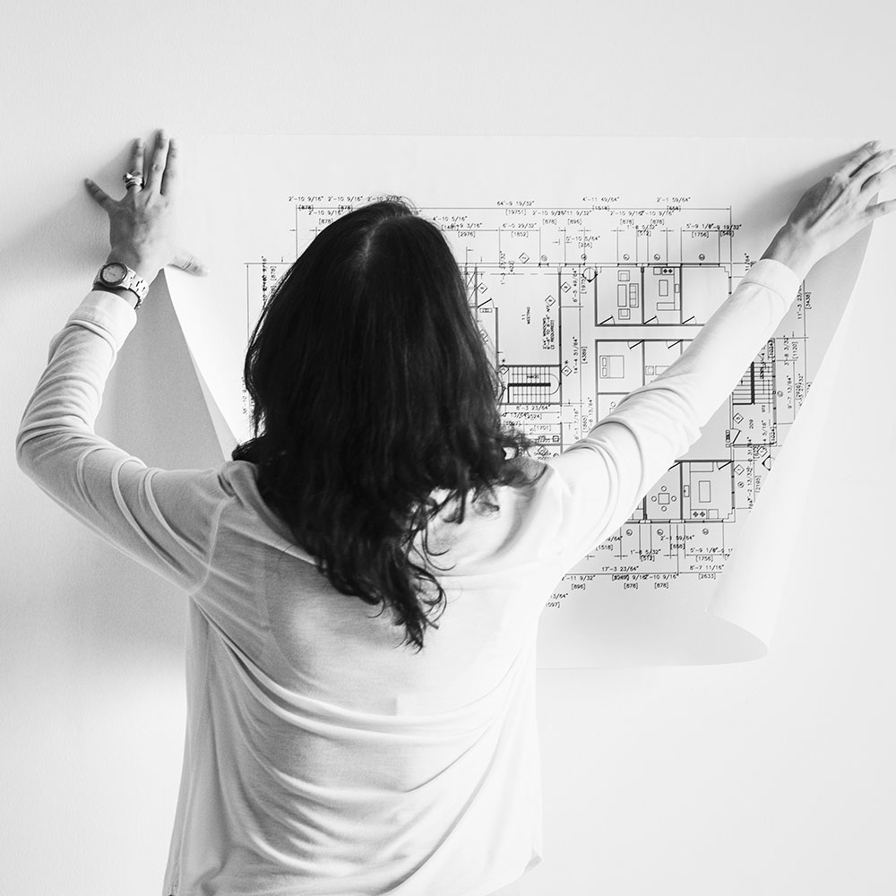 Woman attaching a plan print to a wall.